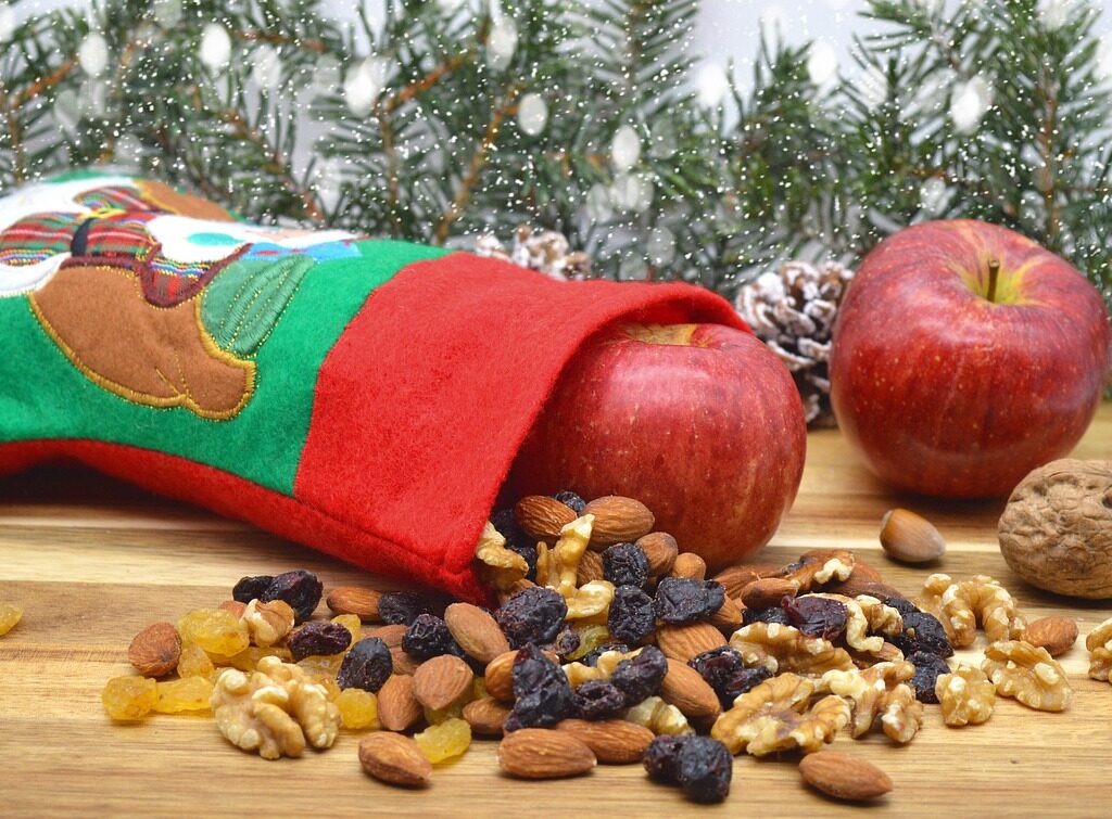Stiefel aus Stoff, der umgekippt im Bild liegt, davor Nüsse und Äpfel.