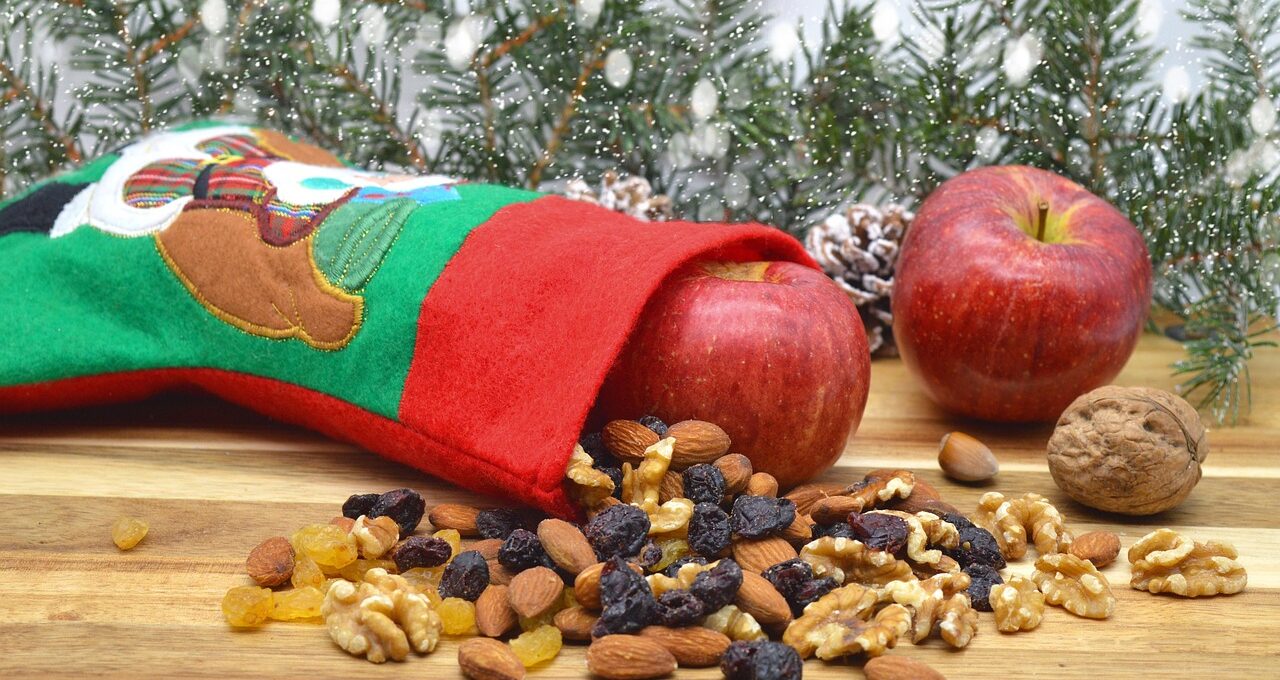 Stiefel aus Stoff, der umgekippt im Bild liegt, davor Nüsse und Äpfel.